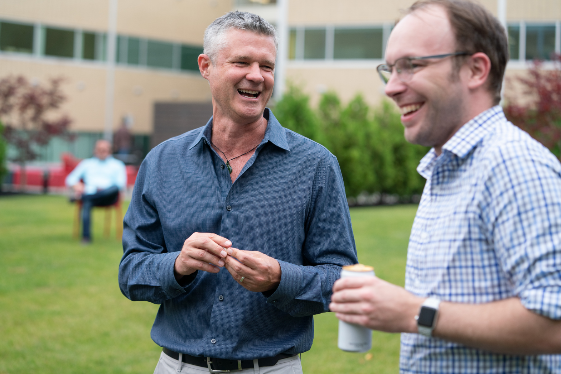 Image of two laughing employees standing in an outdoor office courtyard