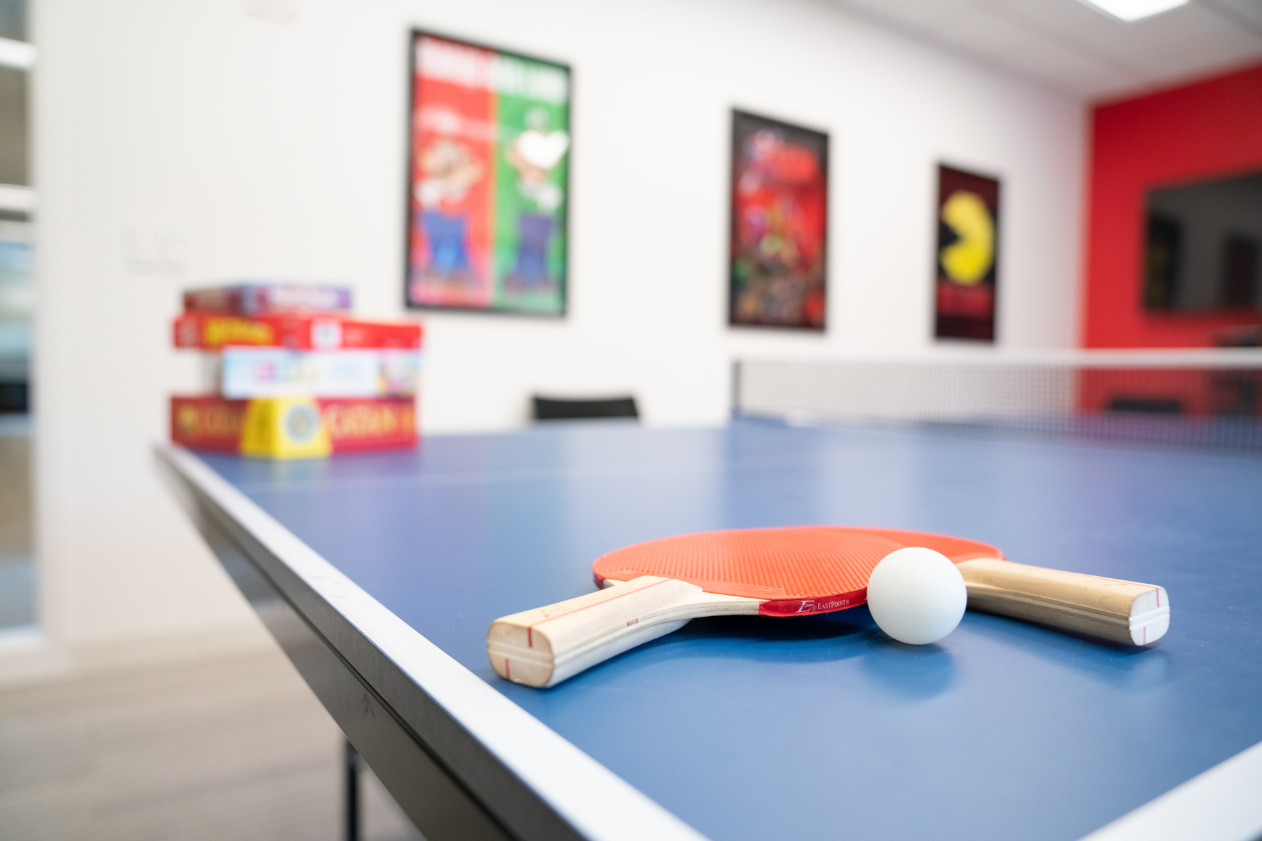 Image of paddles and a ball on a ping pong table in a game room