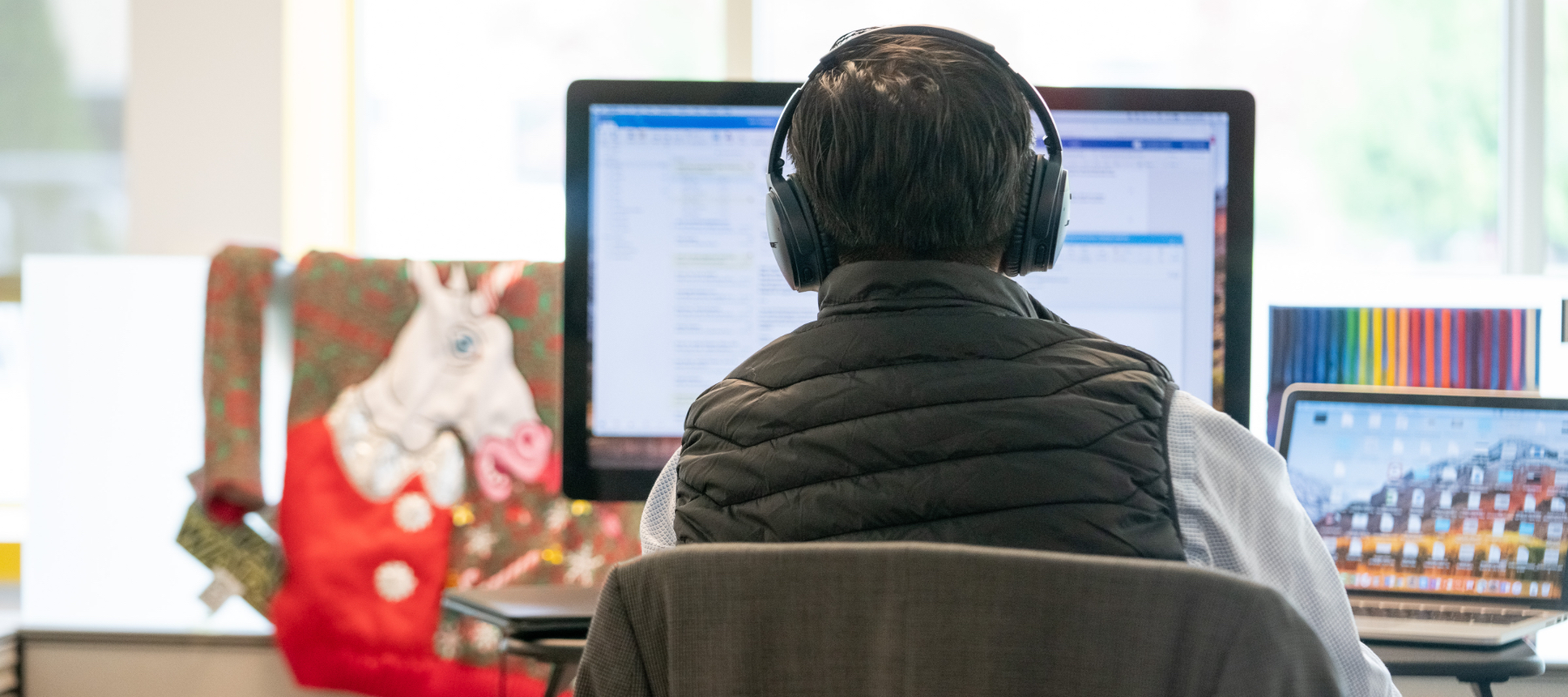 Image of an employee with headphones on sitting at a computer