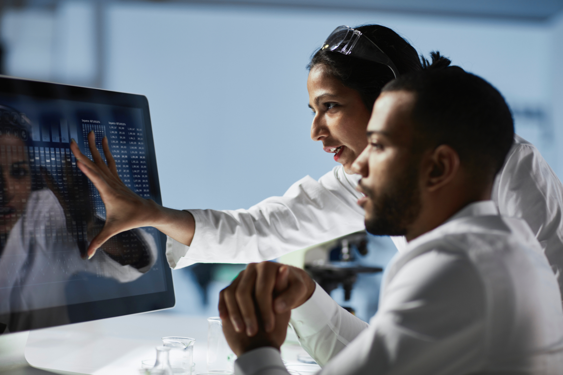 Image of two hospital lab workers reading the screen of a desktop computer