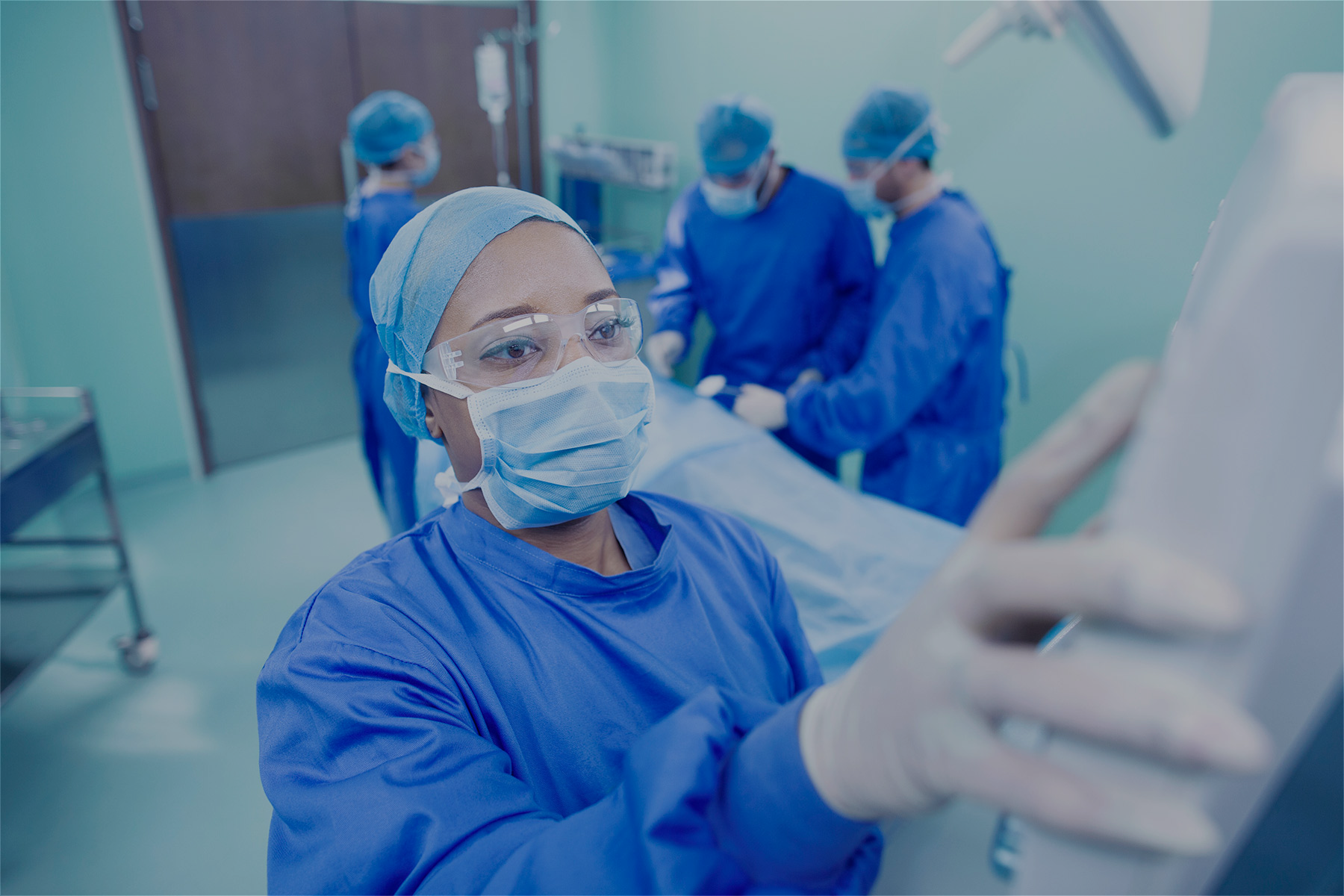 Image of a surgeon in an operating theater with their hand on a medical device 