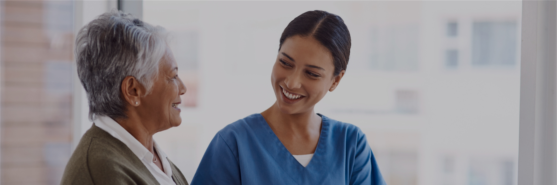 Image of a nurse smiling at a patient and holding her hands