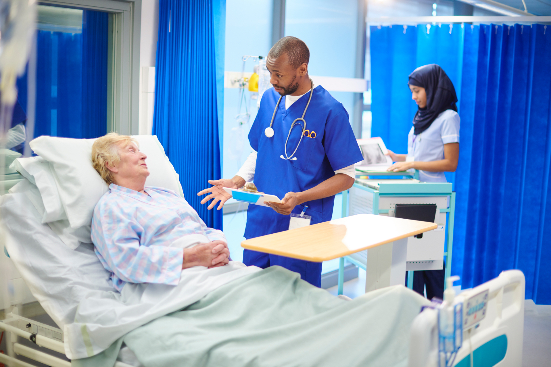 Image of a nurse speaking to a patient lying in a bed