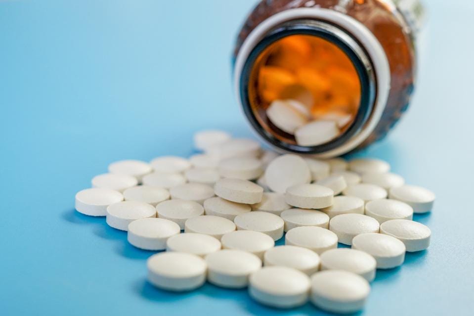 Image of pill bottle laying on its side, with pills spilling out