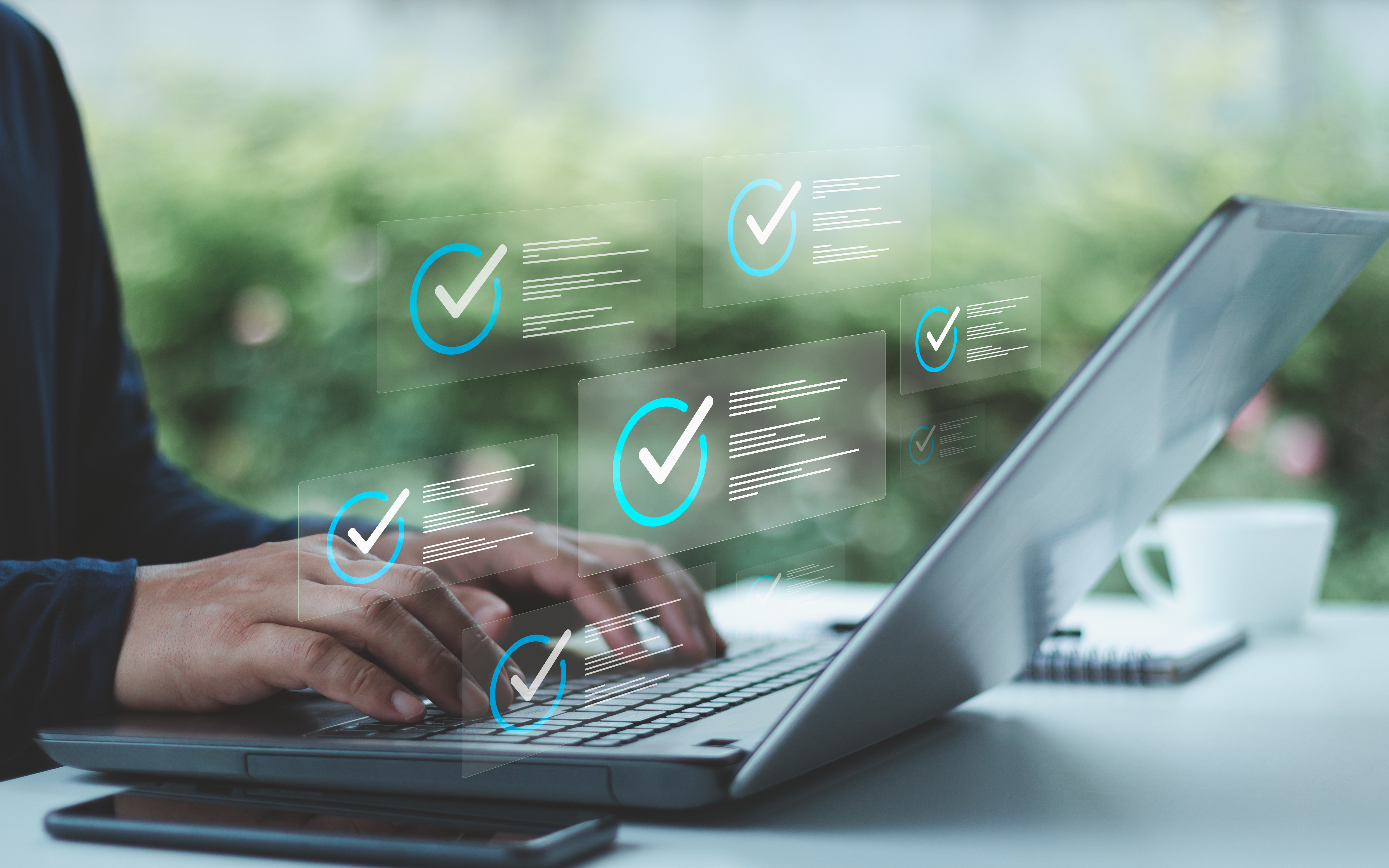 Photo of person typing on laptops with overlaid checkmarks to signify complaince