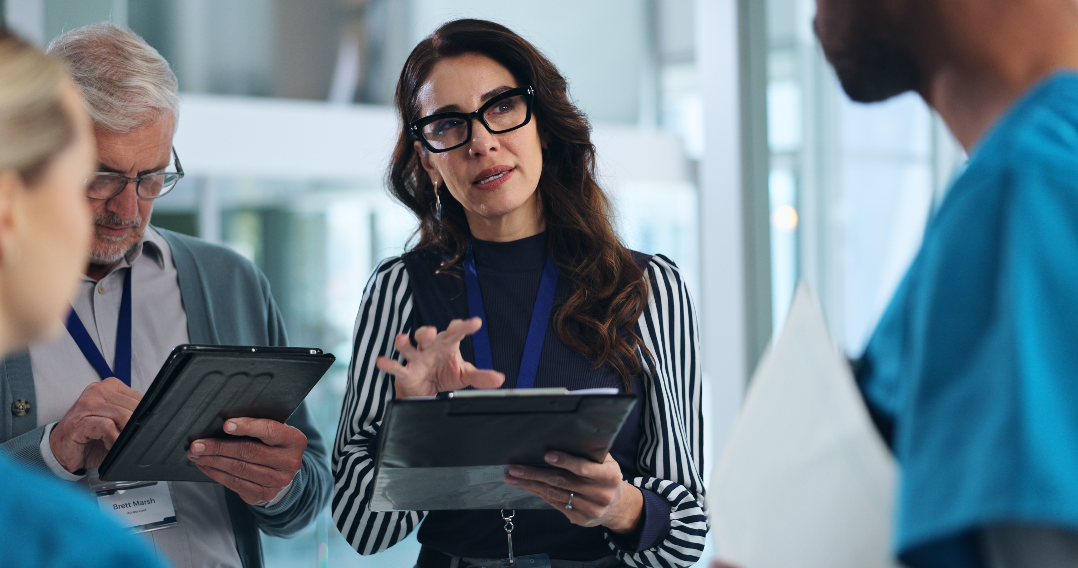 Woman holding a tablet talking with other health professionals