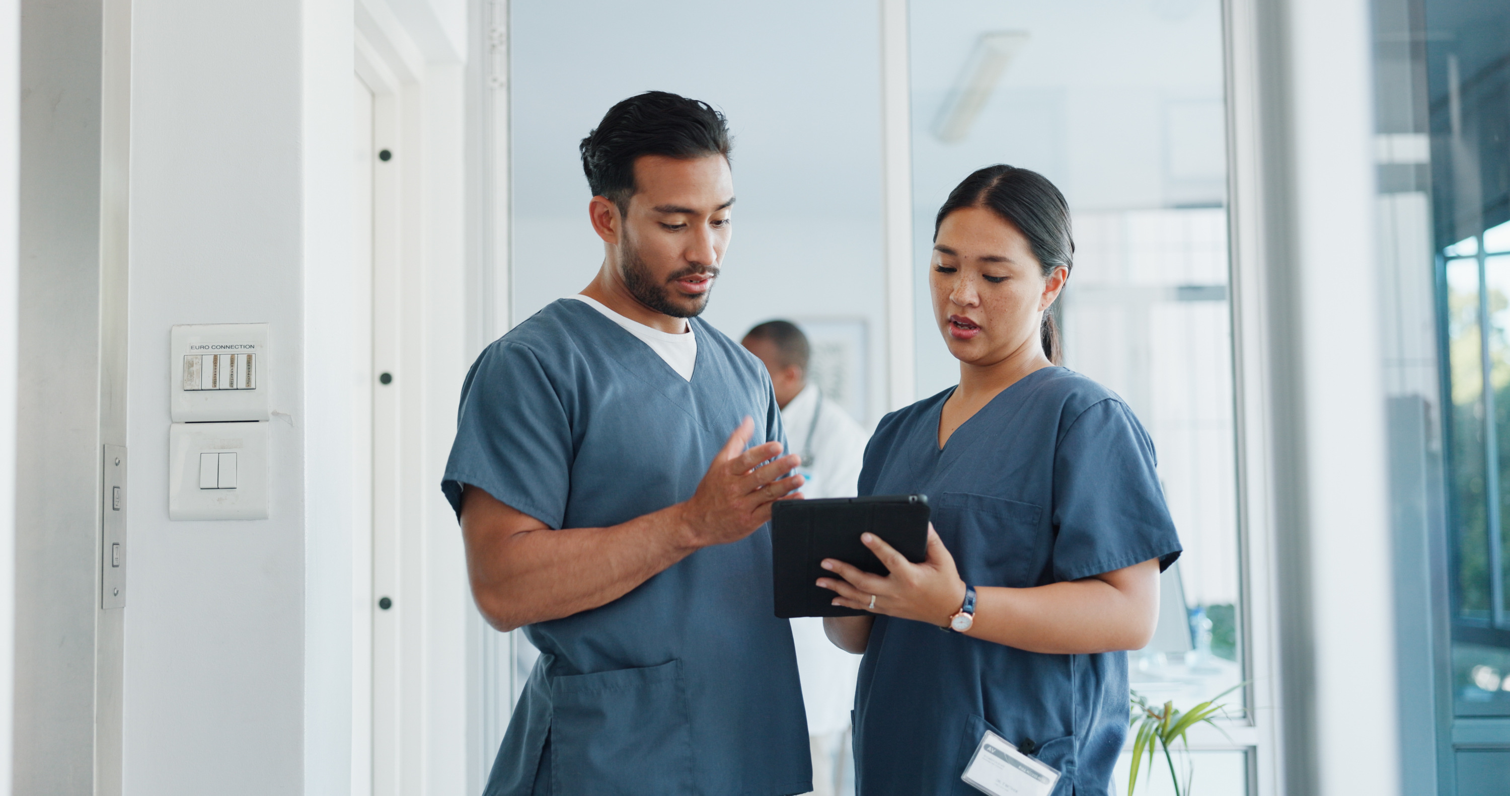 Two nurses talking to each other while looking at a tablet