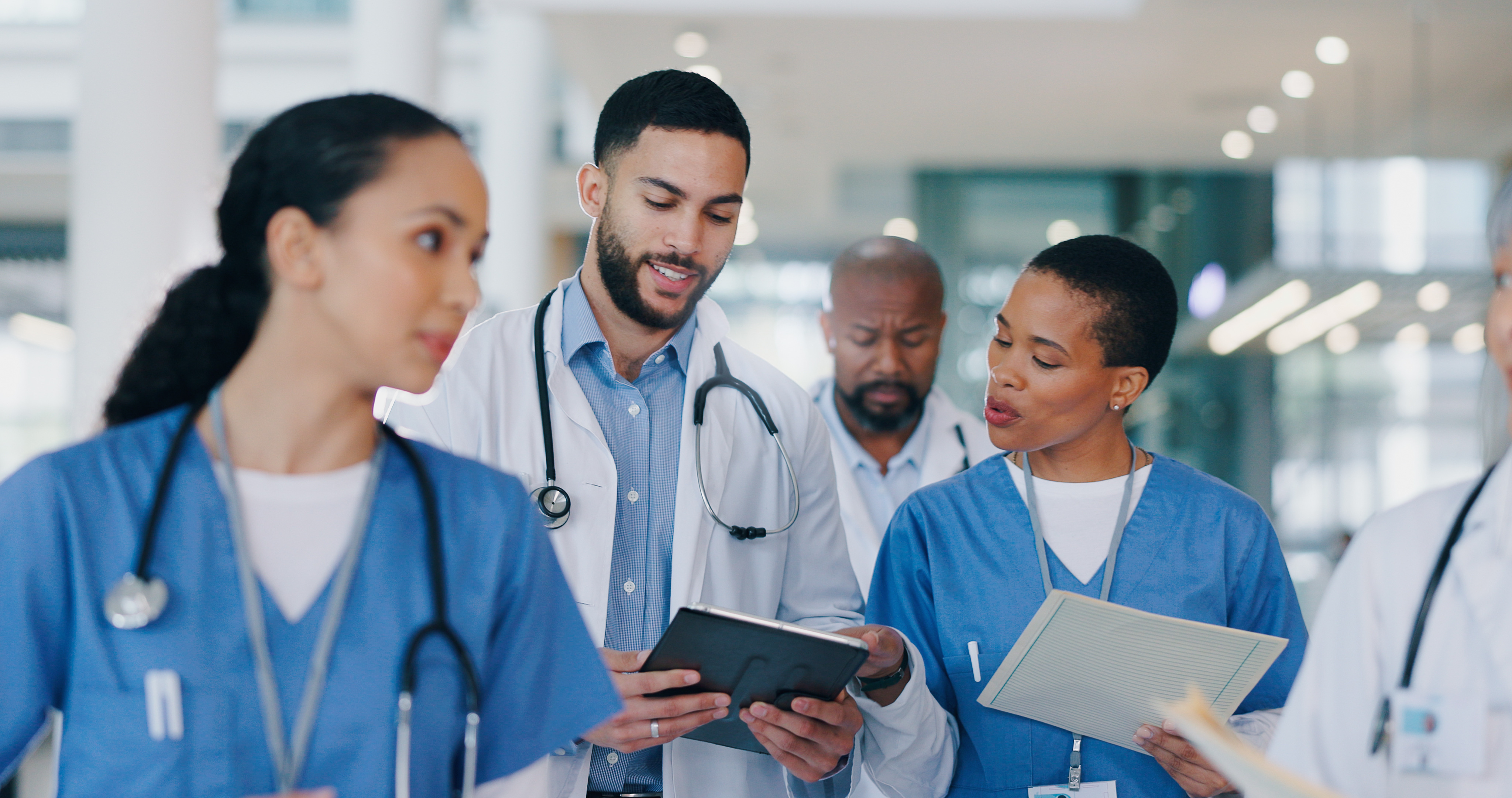 Photo of doctors and nurses walking and talking while using tablet