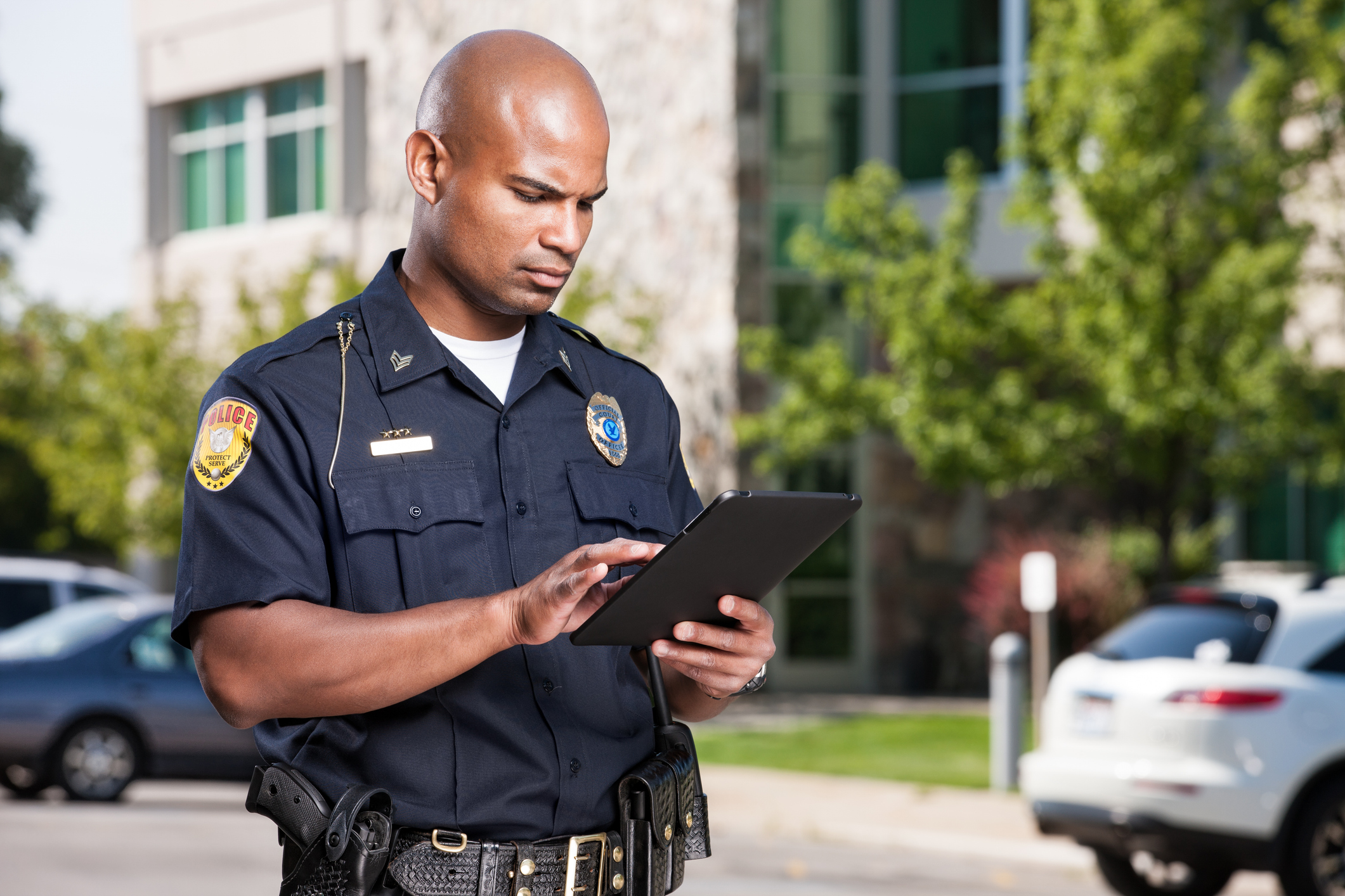 Uniform police officer accessing CJIS information on a tablet on the job