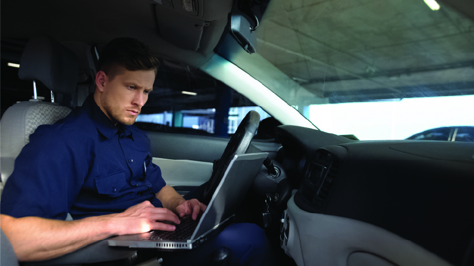 Police officer in a vehicle viewing a laptop