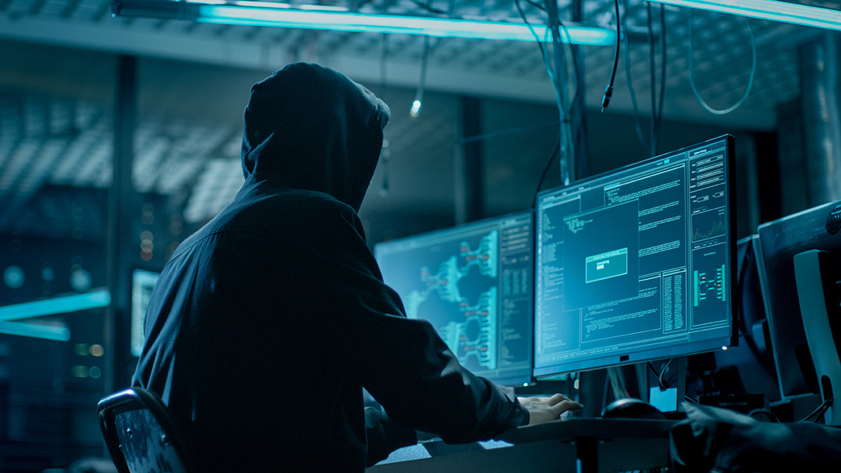 Hacker in dark room with computers